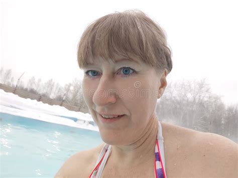adult mature woman takes a selfie in a pool with warm hot termal mineral water in winter and