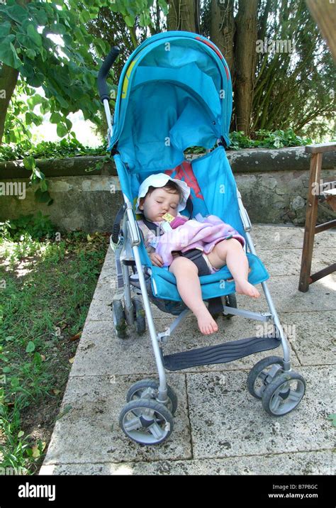 A Baby Girl Lies Asleep In Her Pram In The Shade During A Holiday Stock