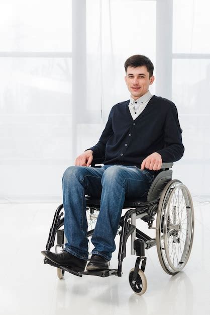 Portrait Of A Smiling Young Man Sitting On Wheelchair Looking At Camera