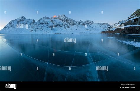 Panorama Of Frozen Lago Bianco Surrounded By Snowy Peaks At Dusk