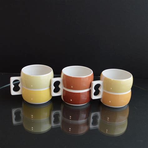 three coffee mugs sitting on top of a black table next to eachother