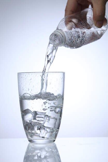 Premium Photo Cropped Hand Pouring Water In Glass Against White