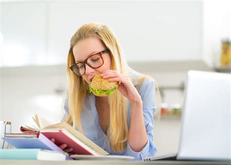 Woman Eating Sandwich While Studying In Kitchen Stock Image Image Of