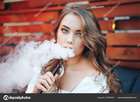 Young woman smoking a hookah outdoors. The pleasure of smoking. Portrait of a smoking young 