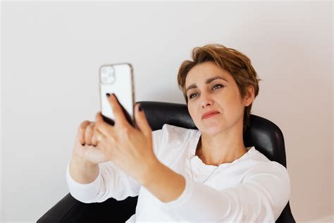 Smiling Woman Taking Selfie On Smartphone While Sitting In Armchair