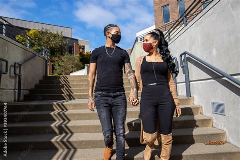 African American Lesbian Couple Wearing Face Masks Holding Hands And Walking Down Stairs Outside
