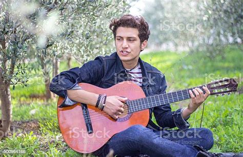 Portrait Of Teenage Boy Playing Guitar In Nature Stock Photo Download