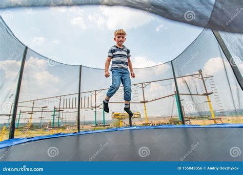 The Boy Jumps On A Trampoline In An Amusement Park Performing Various
