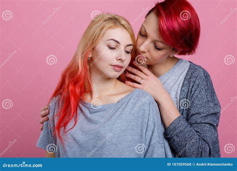 twee lesbische meisjes omhelzen zacht en strelen elkaar op een roze achtergrond stock foto