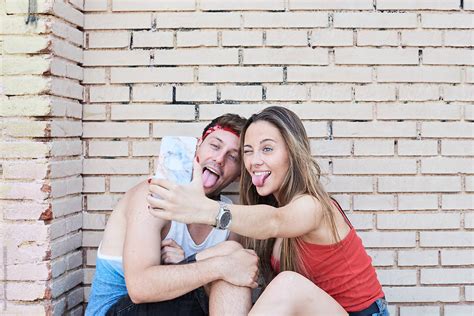 Couple Taking Selfies Against Brick Wall By Stocksy Contributor Ivan