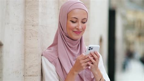 a beautiful arabian woman wearing pink national hijab is chatting using her phone stock footage