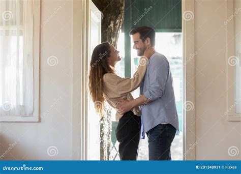 Affectionate Wife Embracing Smiling Husband Meeting At House Door Stock
