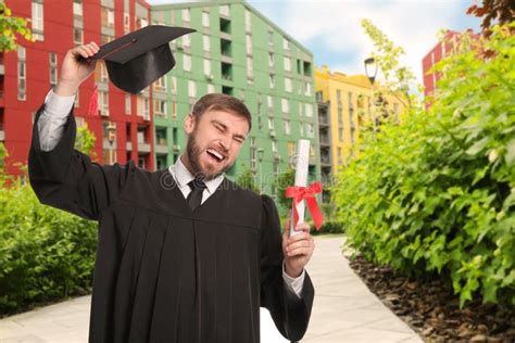 Happy Student With Graduation Hat And Diploma Outdoors Stock Photo