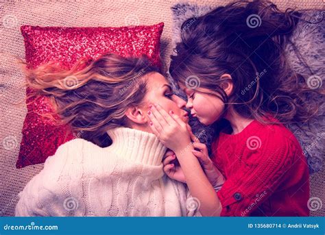 Loving Daughter With Luxurious Hair Kisses Her Mother Lying On The Pillows Care Mother`s Day
