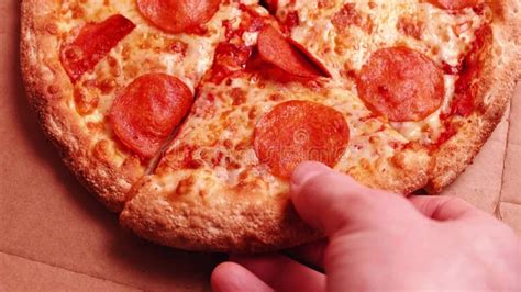 Extreme Close Up Of Hand Taking A Pepperoni Pizza Slice From The