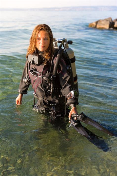 Female Scuba Diving Instructor Standing In Water Wearing A Dry Suit A