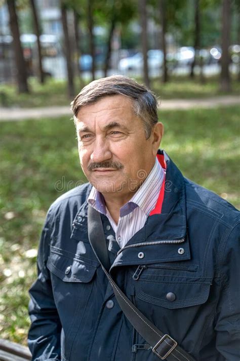 Portrait Of A Pensive Senior Man Sitting On The Bench In The Public