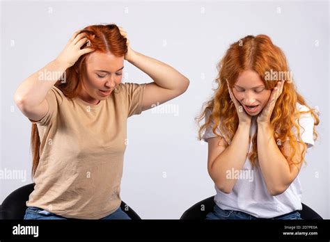 Two Red Haired Girls Sitting On Leather Chairs With Hands On Their