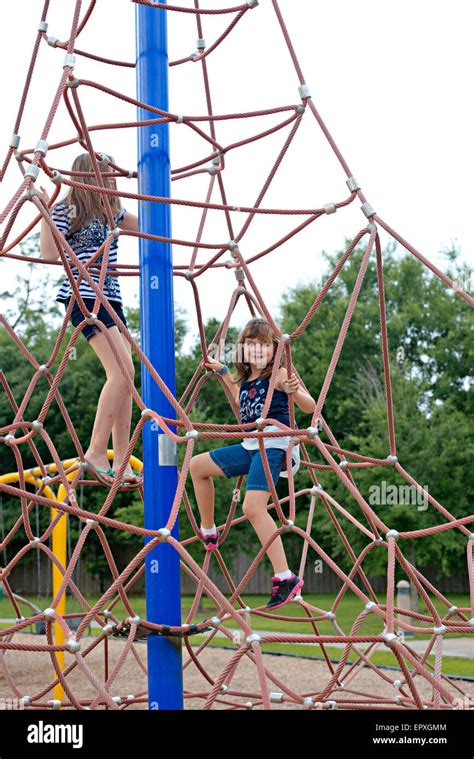Girls Play On Rope Climbing Structure At Outdoor Park Playground Stock