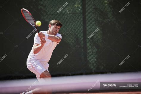 Young Male Tennis Player Playing Tennis Hitting The Ball On Sunny