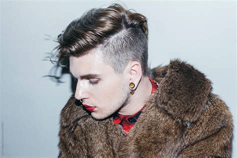 Beautiful Young Man With Red Lipstick And Body Piercing In A Fur Coat