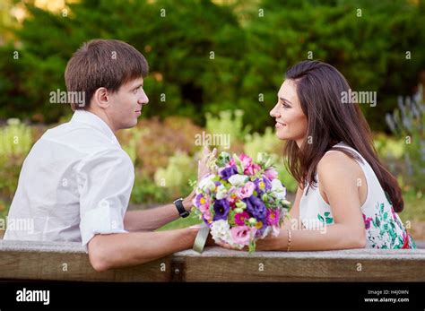 Liebespaar Sitzen Auf Bank Mit Blumenstrauß Stockfotografie Alamy