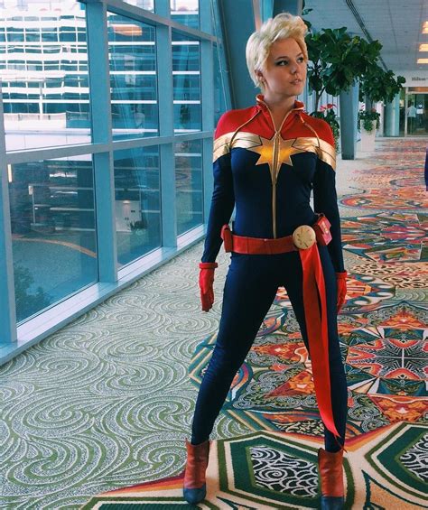 A Woman Dressed As Captain Marvel Stands In An Airport Hallway With Her