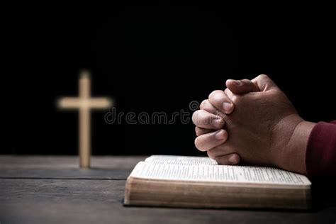 Hands Folded In Prayer On Holy Bible With Cross In Church Concept For