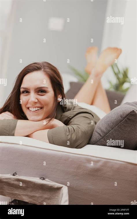 a smiling woman lies face down on her couch at home she has perfectly smooth and shaved legs