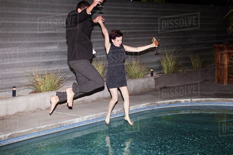 Couple Wearing Clothes Jumping Into Pool At Party Stock Photo Dissolve