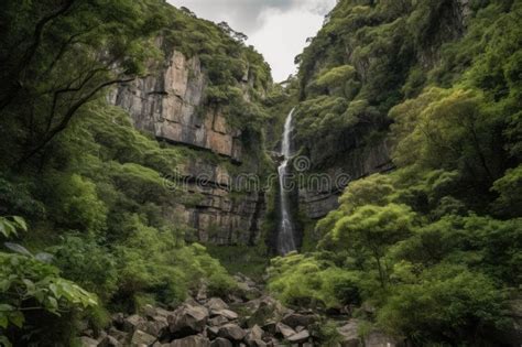 Towering Cliff Face With Cascading Waterfall And Lush Greenery Stock