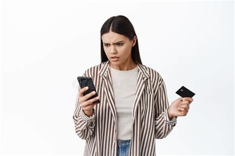 Confused Woman Staring At Her Smartphone And Holding Plastic Credit