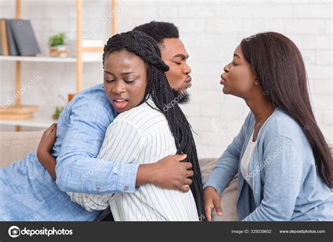 Cheating Afro Man Kissing Another Woman While Hugging With His Wife Stock Photo By Milkos