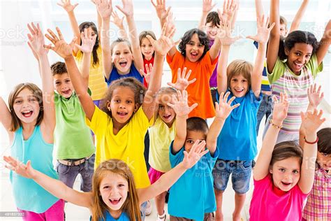 Group Of Excited Children With Raised Arms Looking At Camera Stock