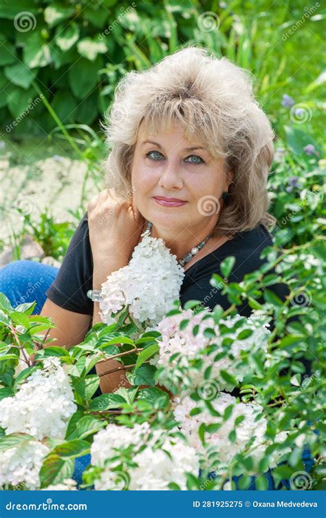 60 Year Old Woman In The Garden A Mature Woman Enjoys The Flowers Of A