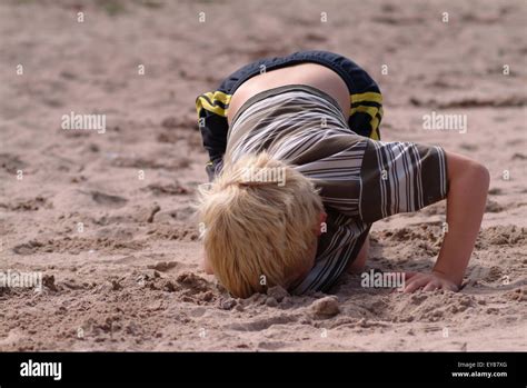 Blonde Haired Boy Digging A Deep Hole In The Sand Stock Photo Alamy