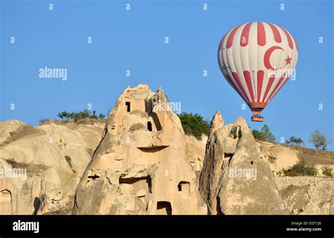 Hot Air Balloon Flying Over Tufa Rock Formations And Ancient Cave