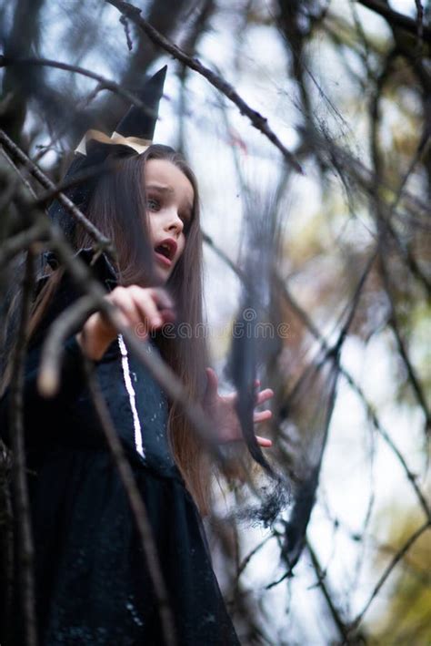 Little Girl Dressed In A Witch Costume Walking In Fall Forest With Fear