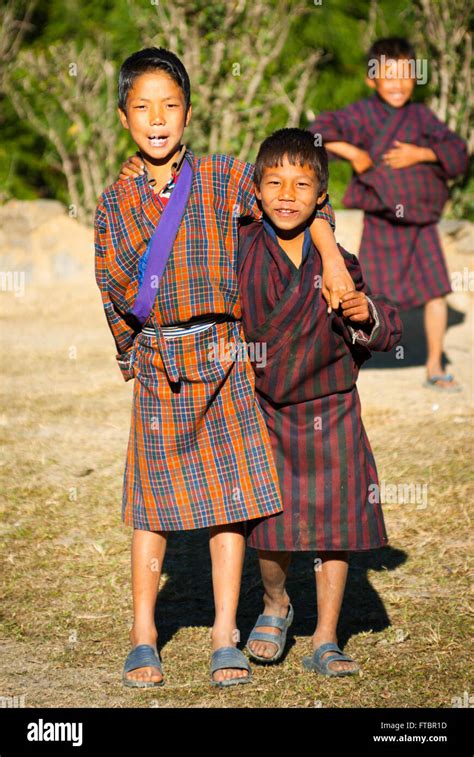 Young Bhutanese Boys Wearing Traditional Striped Gho Robe In Nimshong
