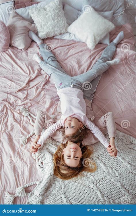 Beautiful Young Mother And Her Little Daughter Are Lying Together On The Bed In The Bedroom
