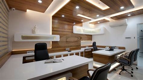 An Office With Two Desks And Chairs In The Center Along With Lights On