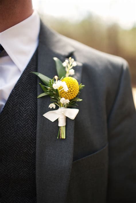 The boutonnieres for the groomsmen, fathers, and grandfathers; Groom wears charcoal grey suit, yellow boutonniere ...