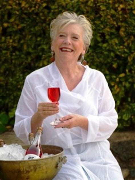 A Woman Holding A Glass Of Wine In Her Hand While Sitting On A Stone Bench