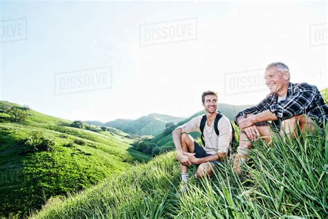 Caucasian Father And Son Sitting On Grassy Hillside Stock Photo