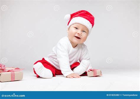 Adorable Baby Wearing A Santa Hat Opening Christmas Presents Stock