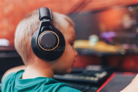 Little Boy Playing Games On Computer In Headphones With Microphone