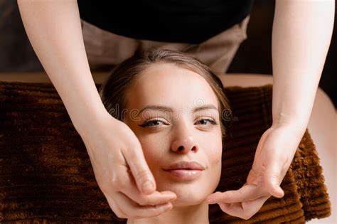 masseur is making facial massage in spa for model with perfect skin beauty procedure stock