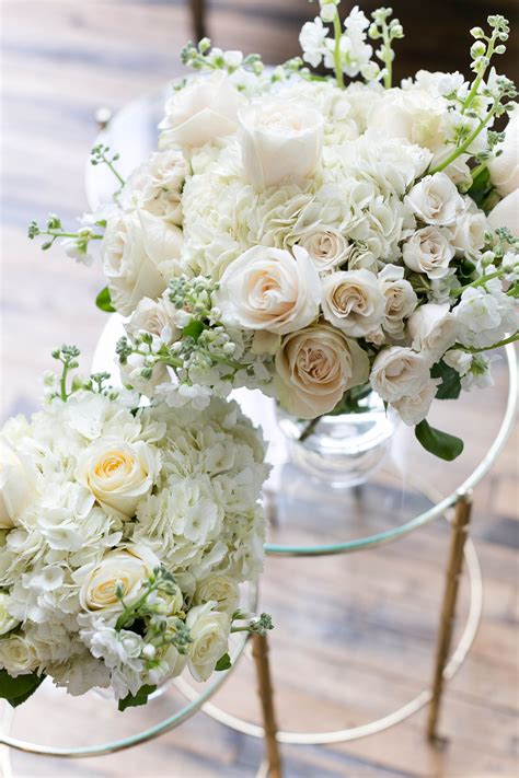 Two Vases Filled With White Flowers Sitting On Top Of A Table Next To