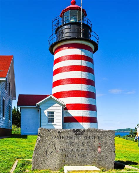 A Lighthouse With A Red And White Stripe On Its Side In The Grass