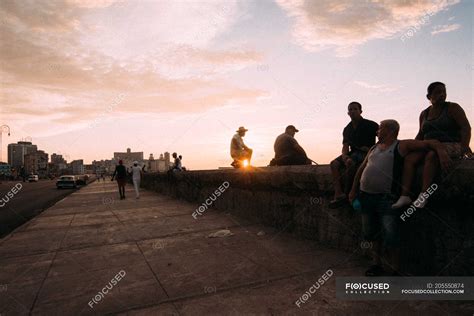 Cuban City Dwellers Chilling On Pedestrian Concrete Waterfront On